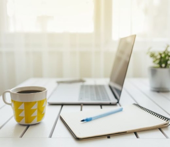A computer on a desk next to a cup of coffee